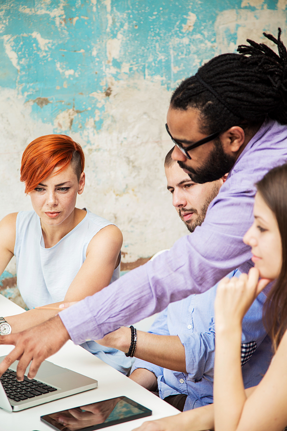 A diverse group of individuals engaged in conversation while seated around a table in a collaborative setting.